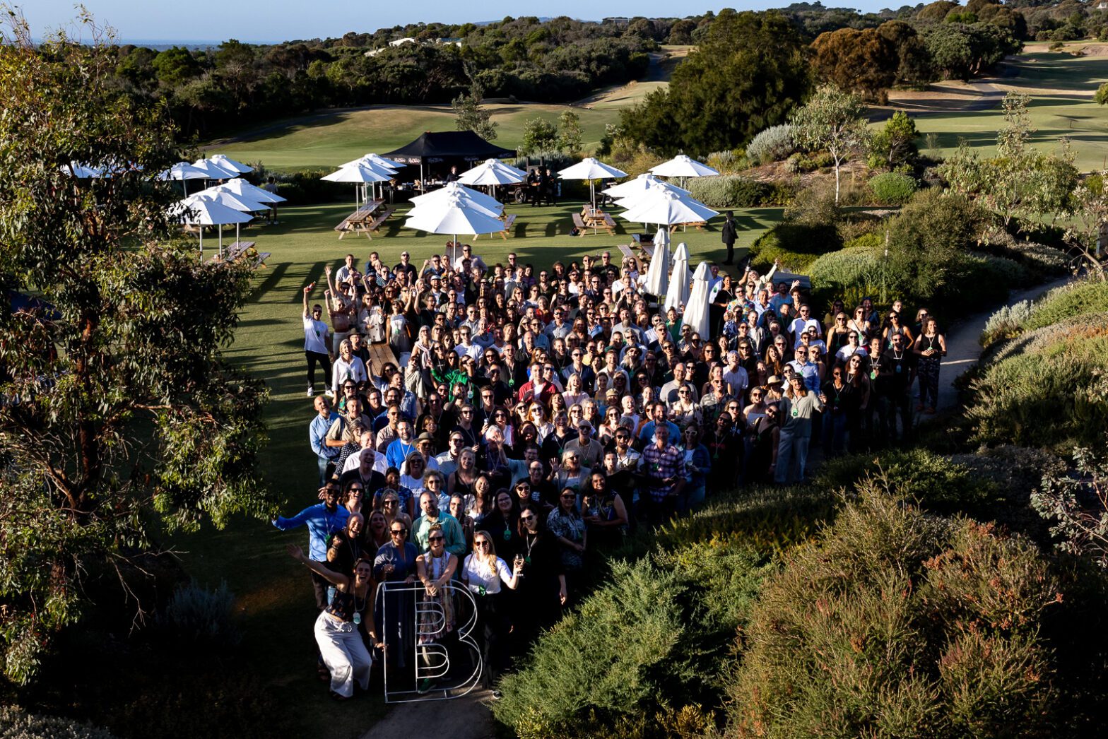 A large group of people standing outdoors smiling at the camera.