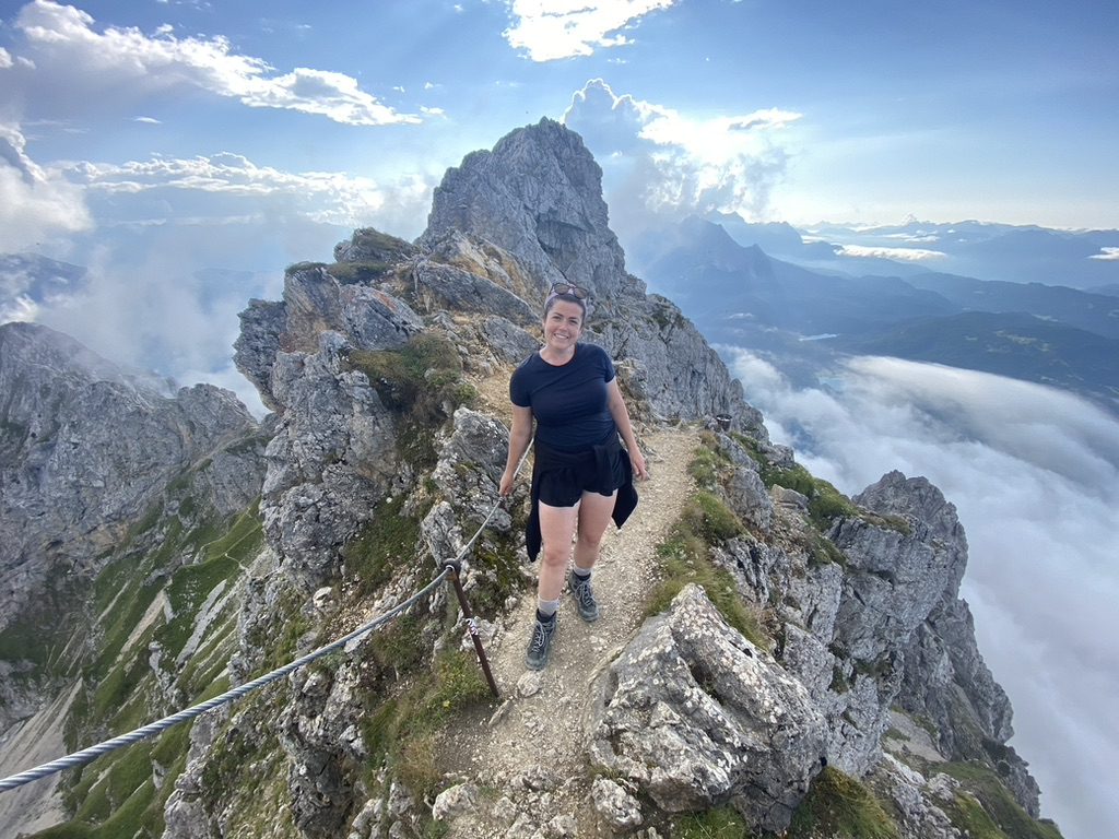 Woman stands atop a mountain peak in the Alps, Germany.