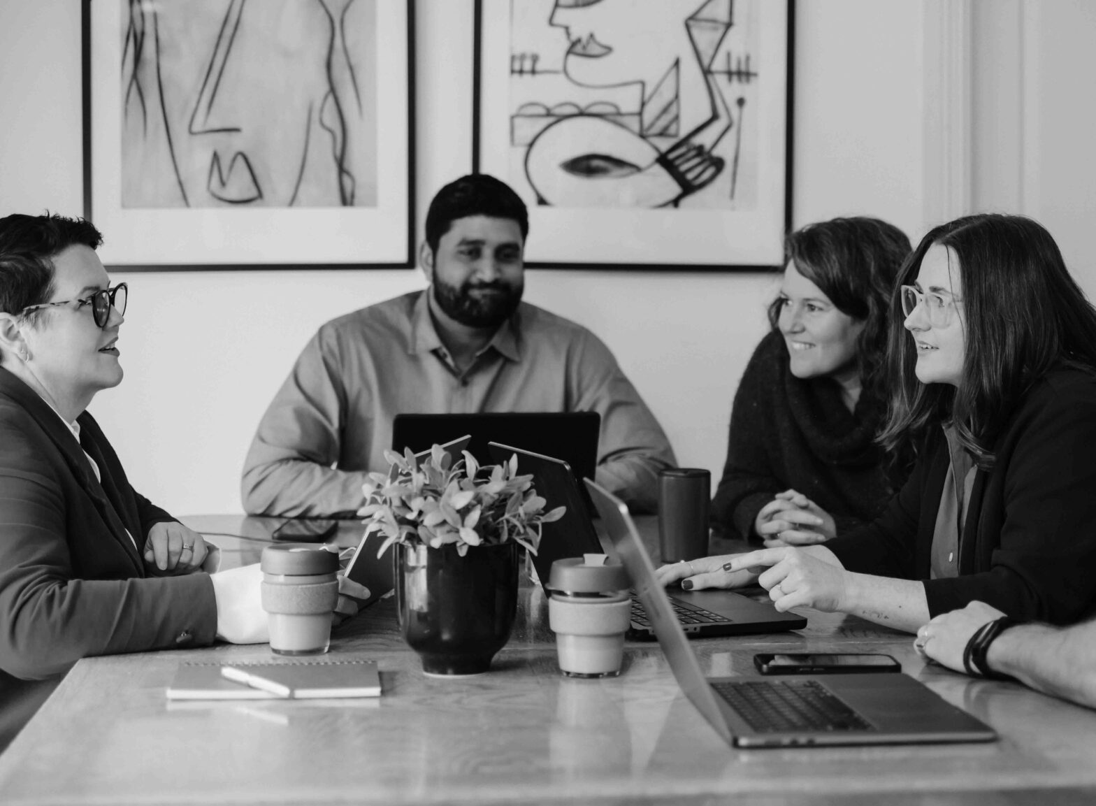 Team working around an meeting table with laptop in foreground