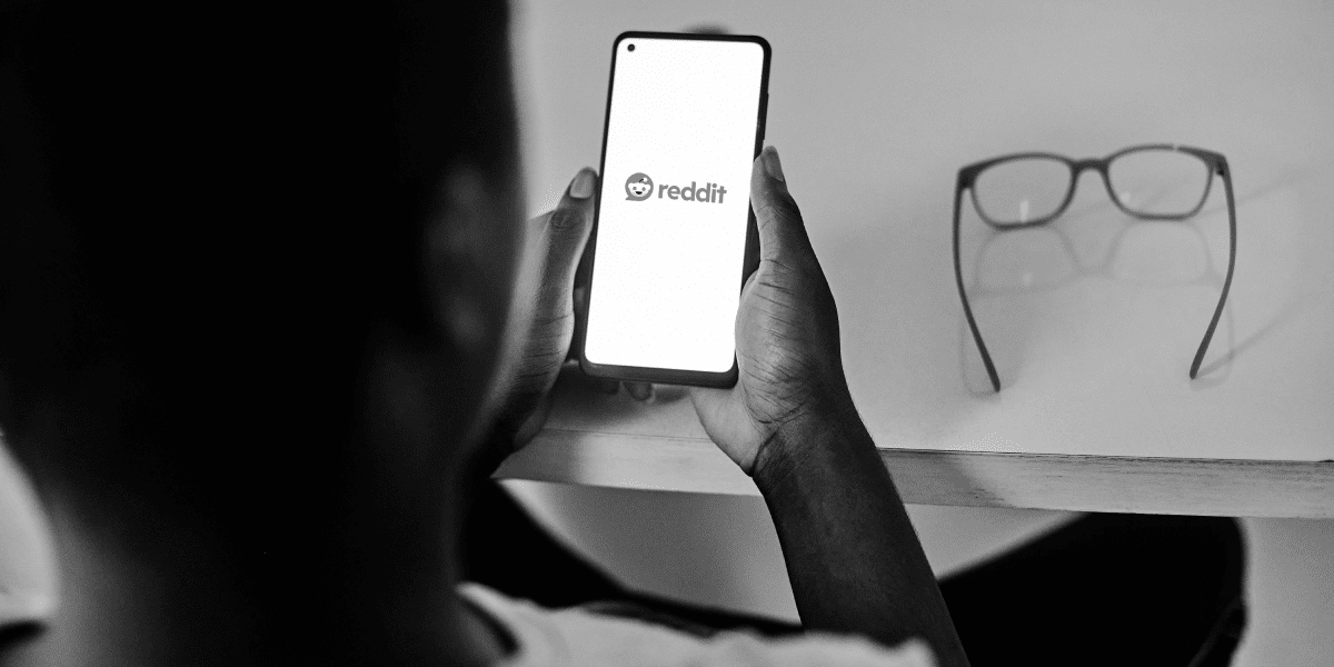 Person holding a smartphone with Reddit shown on the screen.