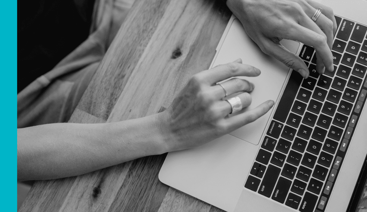 Black and white image of women's hands pictured typing on a laptop computer keyboard